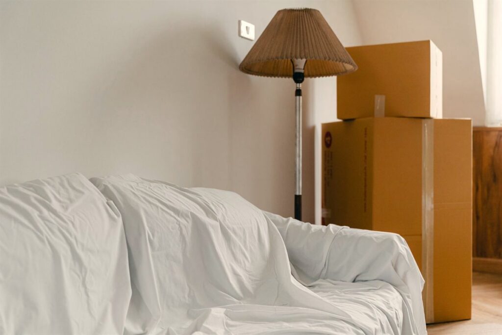 Räumung in vollem Gang – abgedeckte Möbel und gestapelte Umzugskartons in einer Wohnung